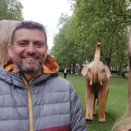 Man with short hair smiling in front of an elephant statue