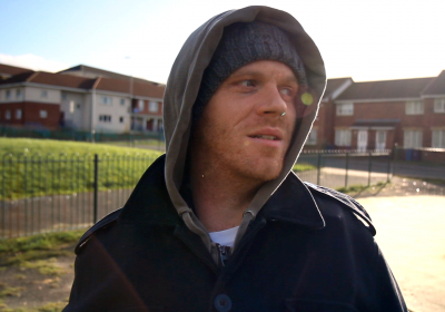 The Divide film cover - a young man wearing a hoodie looking sideway 