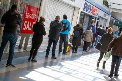 People practicing social distancing whilst queuing for a shop