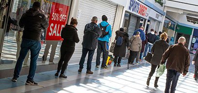 People practicing social distancing whilst queuing for a shop